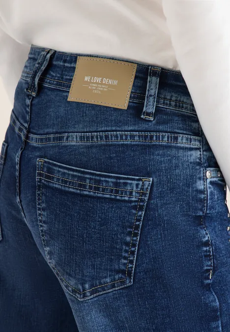 Rückansicht einer Person in dunklen Jeans mit braunem Lederpatch am Bund und weißem Oberteil